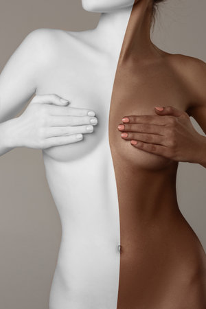 Faceless image of beautiful slim female body with tanned and white skin color against grey background. Female health careの写真素材