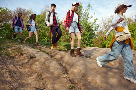 Group of friends, young people, men and women in comfortable casual clothes going hiking, walking in...