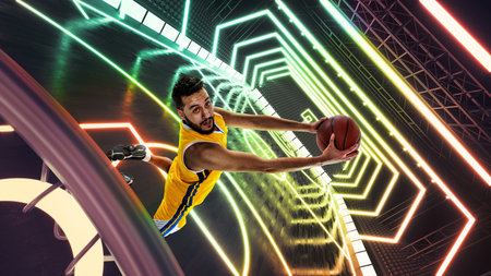 Dynamic image of young man, basketball player in uniform in motion, jumping with ball against 3D neon colored backgroundの写真素材