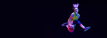 Young girl, basketball player in motion against black studio background in neon light