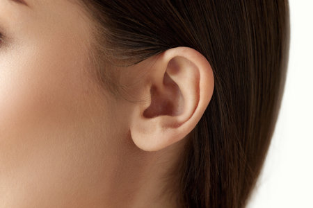 Close-up cropped image of female head part, ear against white studio background. Taking care after healthの写真素材