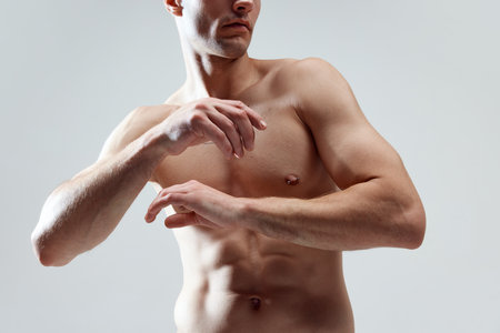Cropped image of muscular, attractive, relief male body, breast, hands against grey studio background. SHirtless modelの写真素材