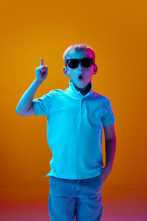 Idea. Portrait of little boy, child in casual clothes and sunglasses raising finger up against...