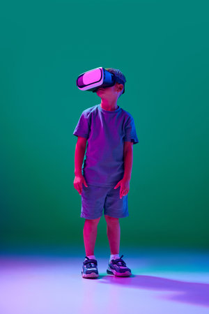 Little boy, child wearing vr glasses against cyan studio background in neon light. Online games, moviesの写真素材
