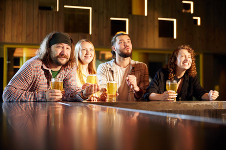 Young emotional people, friends, sport fans visiting bar, drinking beer, watching sport match translationの写真素材