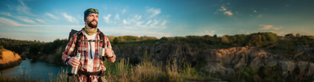 Young man going hiking on hills. Man standing on peak of beautiful mountain and enjoying...