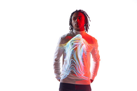 Surrealism. Handsome young guy with colorful neon filter stripes reflection on body posing against white background in neon lightの写真素材