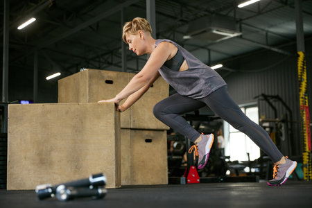 Sportive, fit, mature woman training in gym, doing full-body exercises with fitness equipment. Weight-loss and toned bodyの写真素材