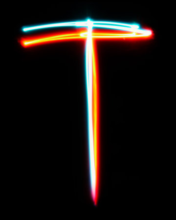 Letter T of the alphabet made from neon sign. The blue red light image, long exposure with colored fairy lights, against a black backgroundの写真素材