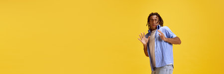 Portrait of young emotive man in casual clothes showing face of fear against yellow studio...
