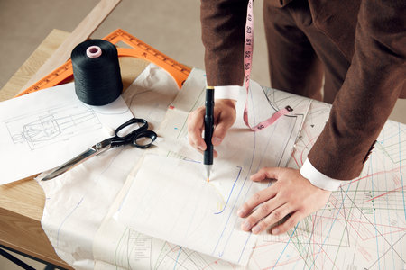 Top view of male hands, fashion designer making professional sketches on clothes on table. Creating new fashion collectionの写真素材
