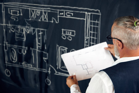 Senior stylish man, professional architect looking on sketches, architectural drawings, creating new projects for buildingの写真素材