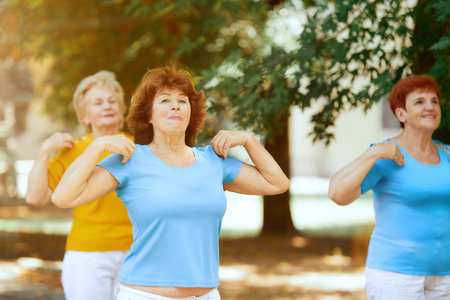 Group of senior people, women, training, doing outdoor workout in city park on warm sunny morning.の写真素材