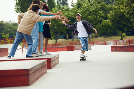 Teen boy in casual clothes skateboarding in skate park, outdoors, having fun with friendsの写真素材
