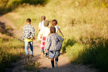 Happy and excited little boys and girls, children in casual clothes running on meadow, exploring nature on warm sunny dayの写真素材