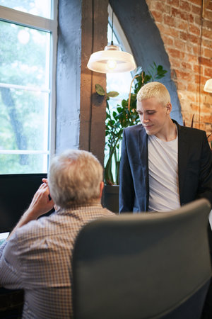 Business communication. Senior and young men talking, discussing project in office. Help and supportの写真素材