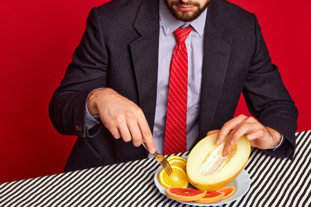 Cropped image of man in official suit touching mean against red background. Passion and hidden tasteの写真素材