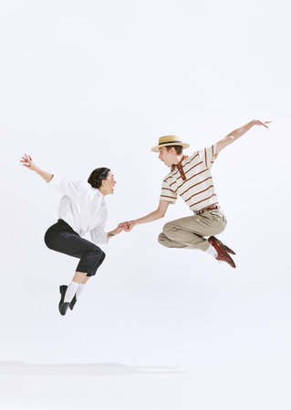 Cheerful, positive young people, man and woman dancing retro dance, having fun isolated on white studio backgroundの写真素材