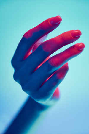 Beautiful, well-kept female hand isolated over blue background in neon light. Natural, nude nails, manicureの写真素材