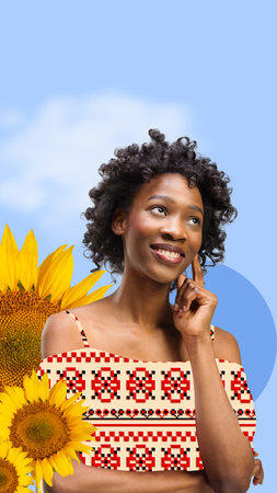 Beautiful, smiling, young african girl wearing clothes with Ukrainian ornament over blue background with sunflowers. Contemporary art collage.の写真素材