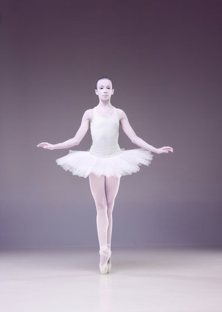 Beautiful talented young woman, professional ballerina, in image of porcelain statue dancing over studio background.の写真素材
