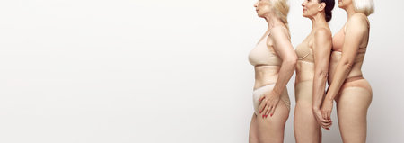 Cropped side view image of female bodies in underwear against grey studio background. Natural body of senior women. Bannerの写真素材