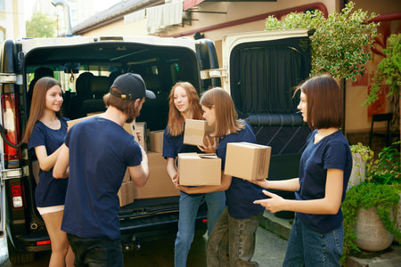 Young people, volunteers in uniform loading boxes into van. Gathering food, clothes, meds for people...