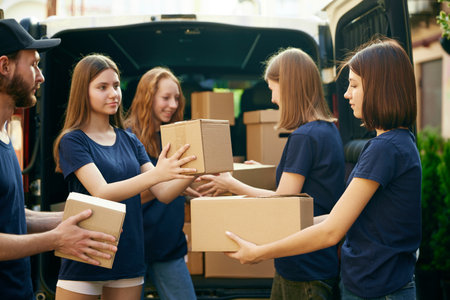 Young people, volunteers in uniform loading boxes into van. Gathering food, clothes, meds for people and animals in needの写真素材