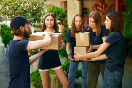 Helpful young people, volunteers gathering humanitarian help for people and animals. Loading boxes into vanの写真素材