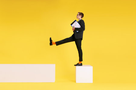 Making analytical report. Businessman, employee with documents against yellow studio backgroundの写真素材