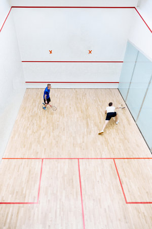 Top view of two young men, friends, sportsmen playing squash on squash court. Competitionの写真素材