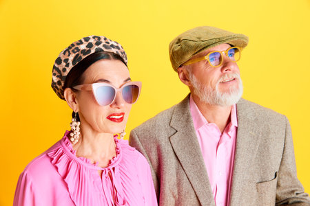 Attractive senior woman in beret, sunglasses and pink blouse standing with handsome bearded man with...