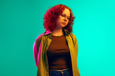 Teen girl in casual clothes standing with dad, unhappy face against cyan background in neon light