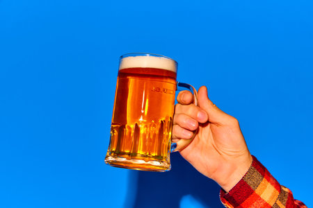 Male hand holding mug with lager foamy beer s isolated on blue background. Degustation. Party. Posterの写真素材