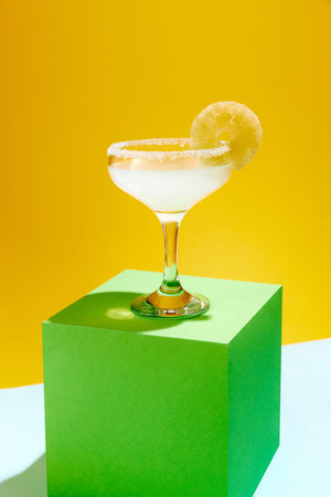 Sweet and sour, popular margarita cocktail with lemon slice decoration isolated over yellow...