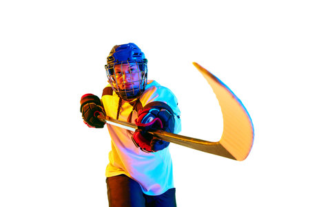 Motivation to win. Young girl, hockey player in helmet and uniform, training, playing against white...