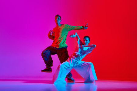 Young talented people, man and woman dancing street style dance, hip hop against pink red background in neon lightの写真素材