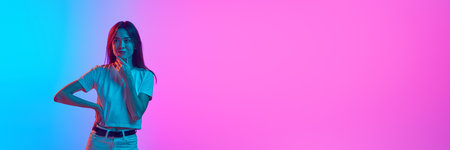 Portrait of young woman posing against gradient pink blue studio background in neon light. Salesの写真素材
