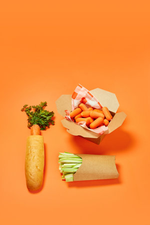 Carrot, celery and mandarin as healthy snacks against orange background. Organic products and healthy foodの写真素材