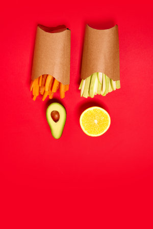 Carrots, celery. avocado and lemon against red background. Flat lay. Health snacks. Organic products and healthy foodの写真素材