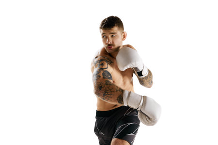 Concentrated muscular shirtless young man, boxing athlete in motion, training isolated over white backgroundの写真素材