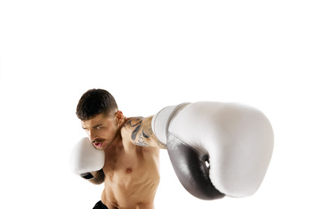 Hook. Muscular, shirtless young man, boxer training, fighting isolated over white backgroundの写真素材