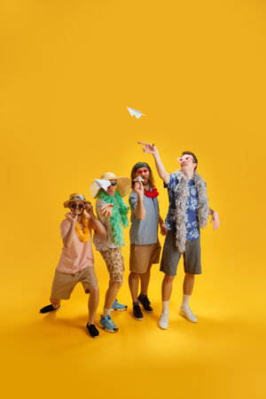 Stylish young men, friends in colorful clothes on summer vacation having fun, playin with paper...