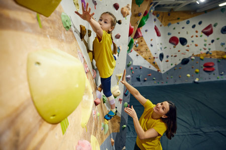 Little girl, child training with instructor, practicing bouldering activity, techniques. Little girl climbing wall, indoor classの写真素材