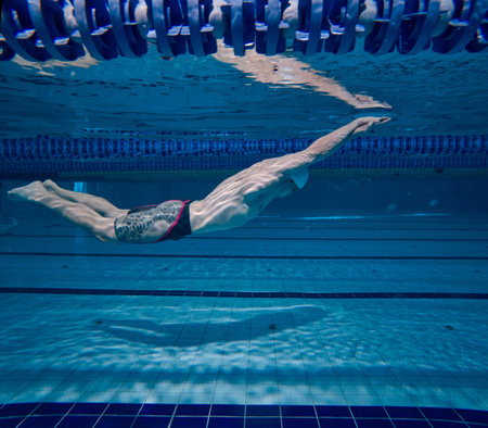 Professional swimming athlete in motion, training, practicing techniques, swimming in pool