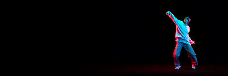 Young girl, hip hop dancer in motion, dancing isolated over black background in neon light. Concept of contemporary danceの写真素材