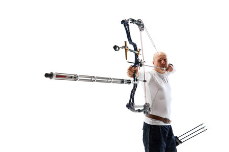 Man in his 40s, archery athlete with bow and arrow aiming at archery target isolated over white...