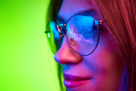 Focused developer, woman wears glasses working on computer looking at programming code which reflecting in glasses.の写真素材