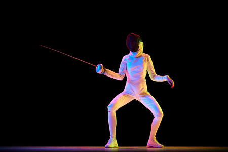 Martial arts and discipline. Fencing, martial art requiring discipline and strategy, perfect for related themes. Female athlete training over black background in neon.の写真素材