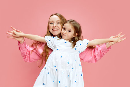 Playful bonding time. Happy smiling young mother spending time with her little daughter against pink studio background. Mothers Day, International Happiness Dayの写真素材